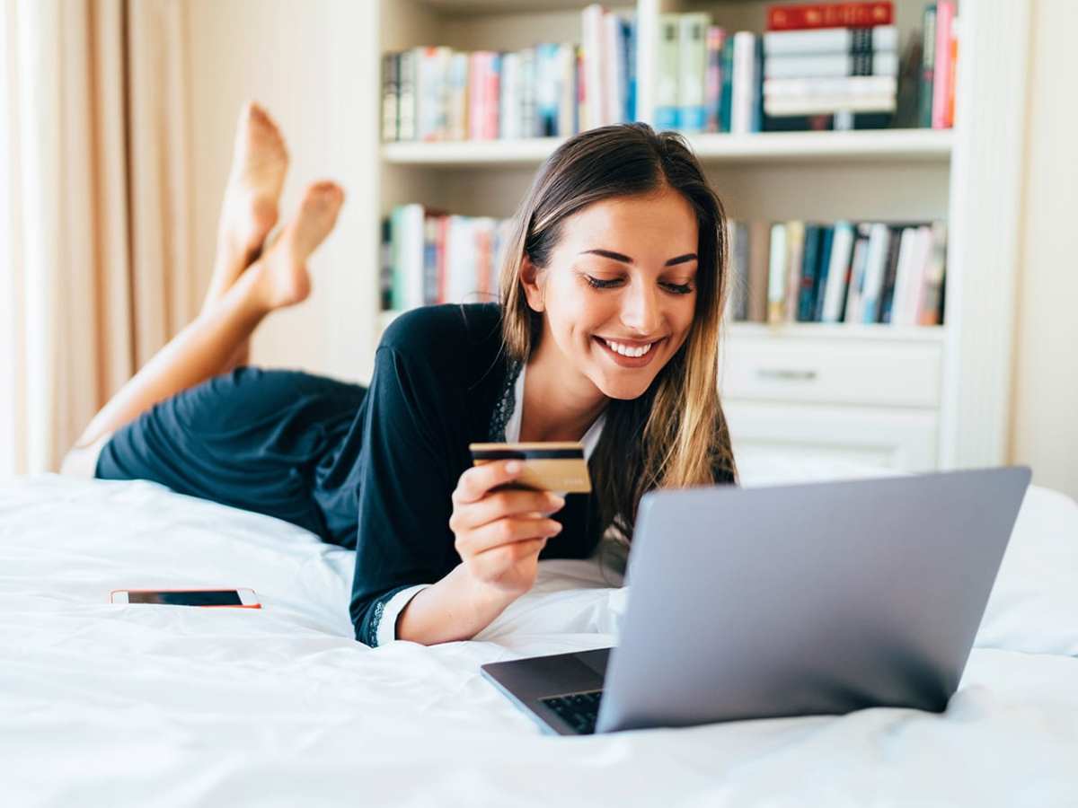 Eine Frau liegt auf einem Bett und nutzt einen Laptop