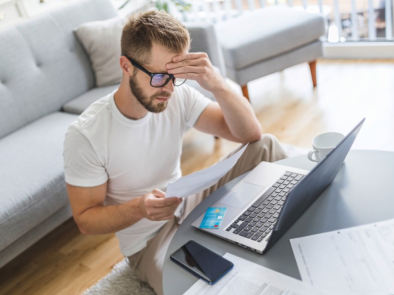 Mann arbeitet mit Notebook im Wohnzimmer