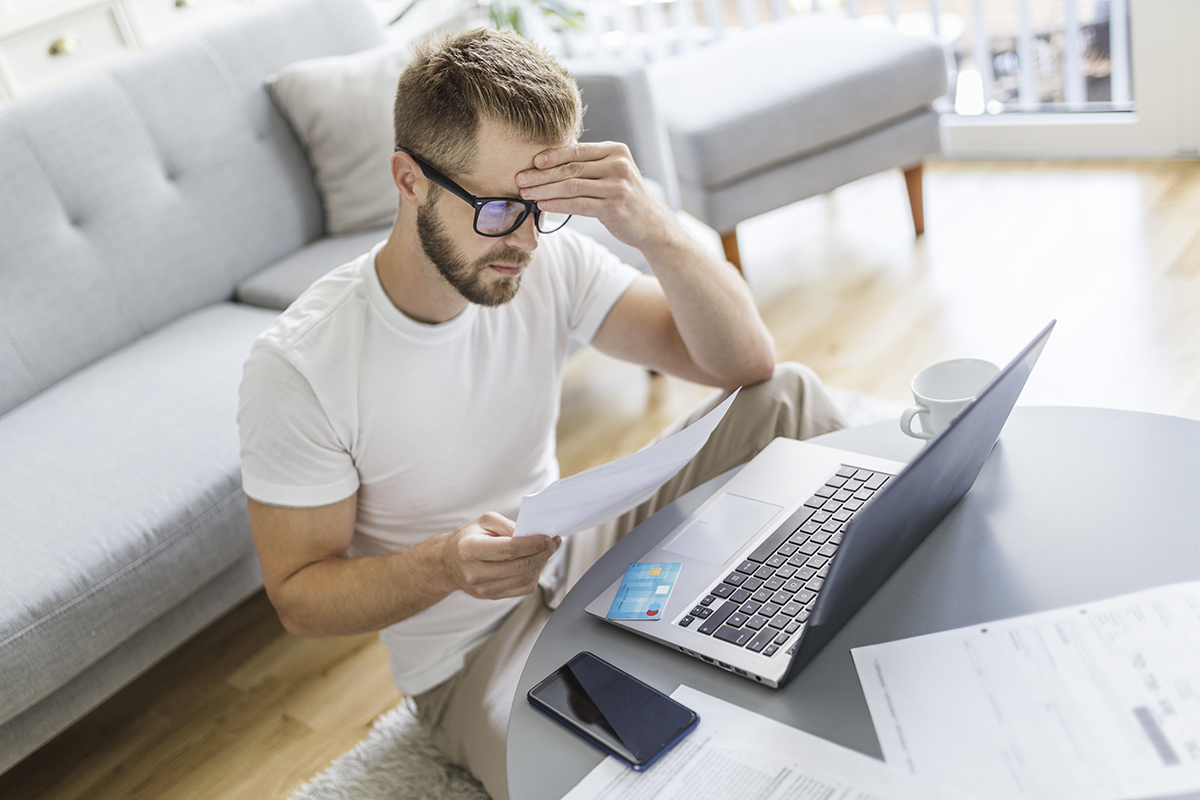 Mann arbeitet mit Notebook im Wohnzimmer