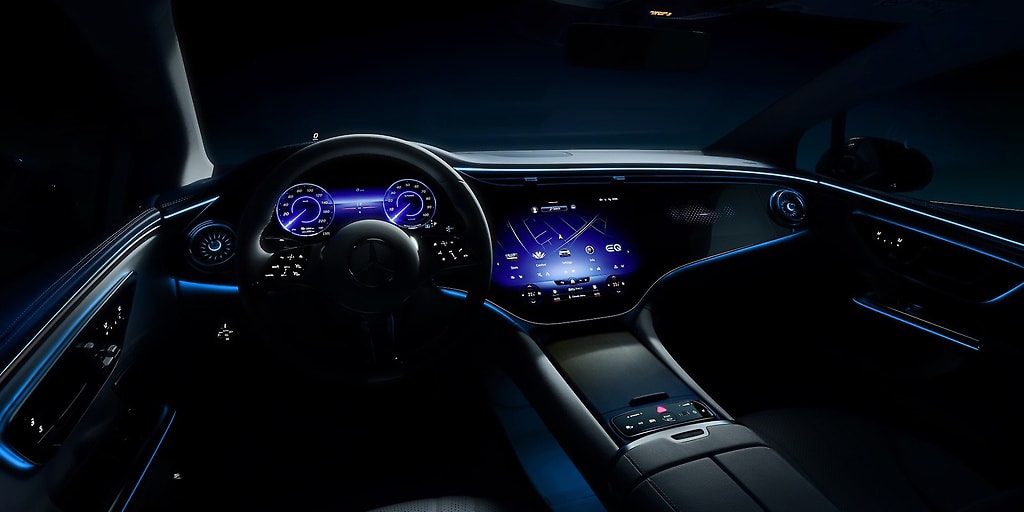 Dunkles Auto-Cockpit vom Fahrersitz aus mit blau leuchtenden Anzeigen