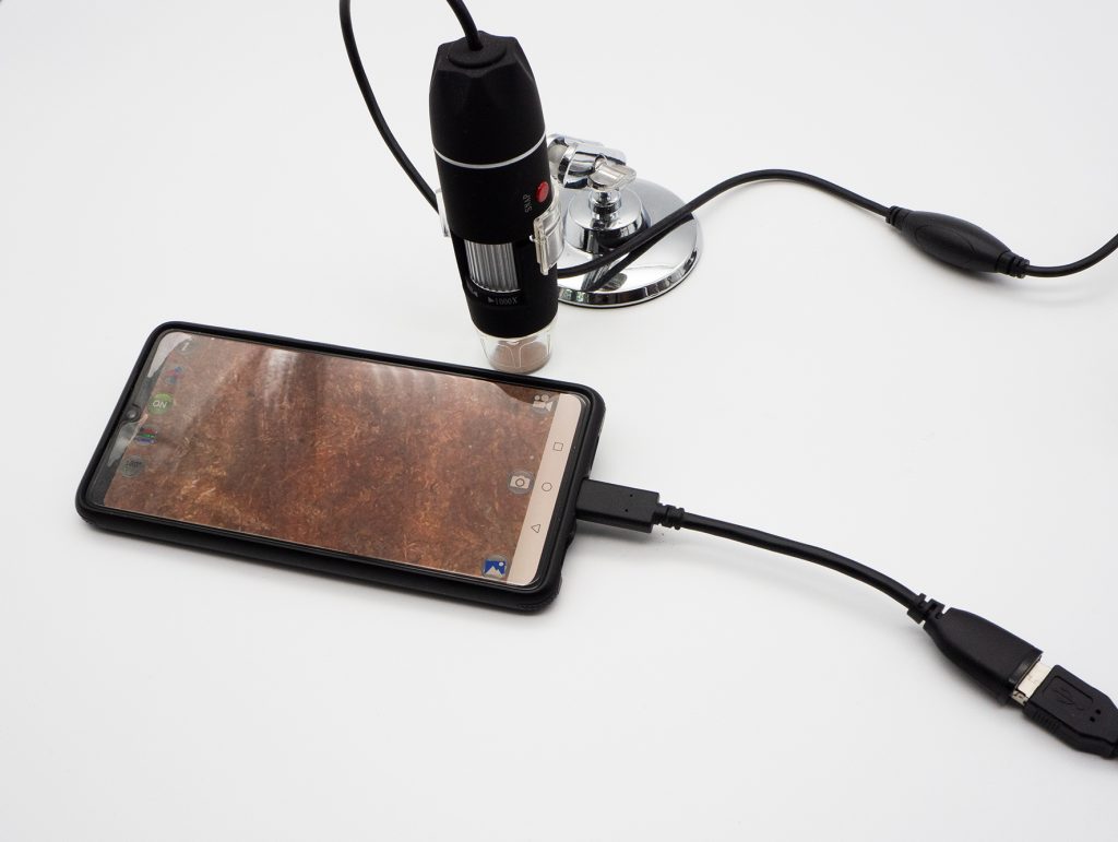 Schwarzes Smartphone mit schwarzem Kabel und kleinem schwarzen mikroskop mit schwarzem Kabel 