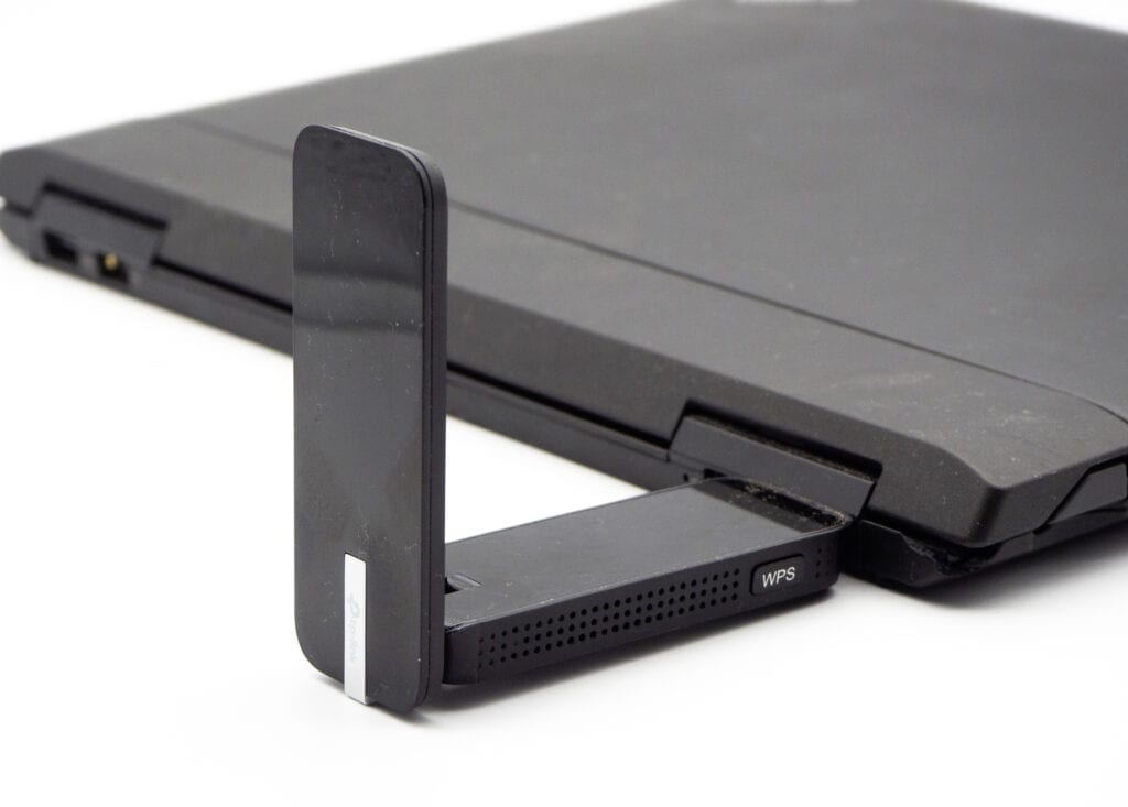 Zugeklapptes schwarzes Notebook von der Seite mit schwarzem rechtwinkelig abstehendem USB-Stick