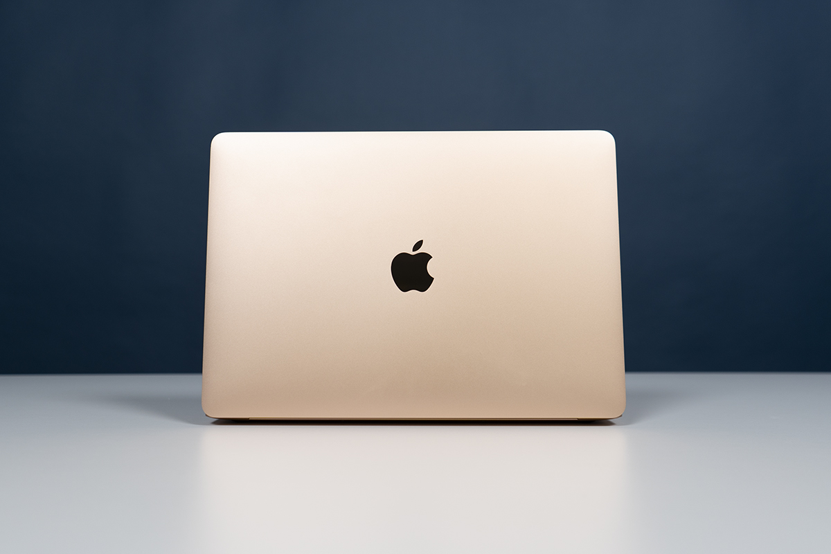 MacBook in gold von hinten vor blauer Wand