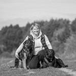 Frau sitzt mit Hunden in der Natur, schwarz weiß