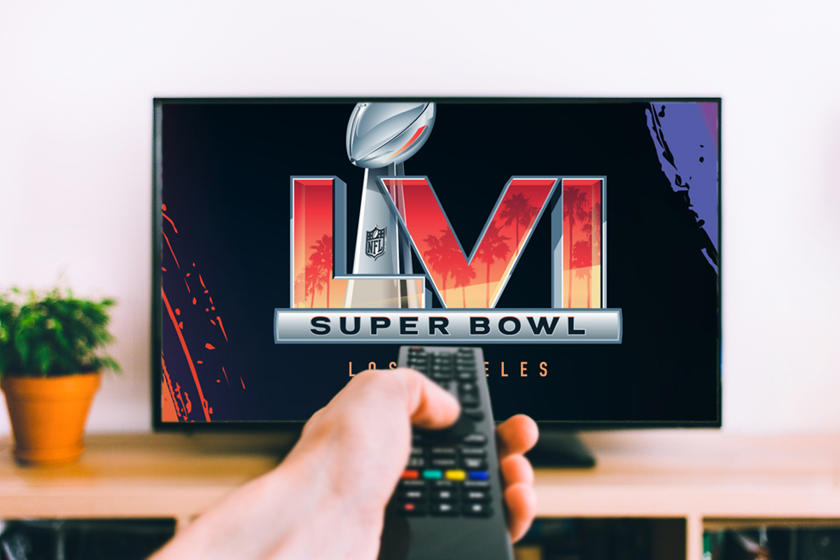 Hand hält Fernbedienung zu Fernseher, der Super-Bowl-Logo zeigt