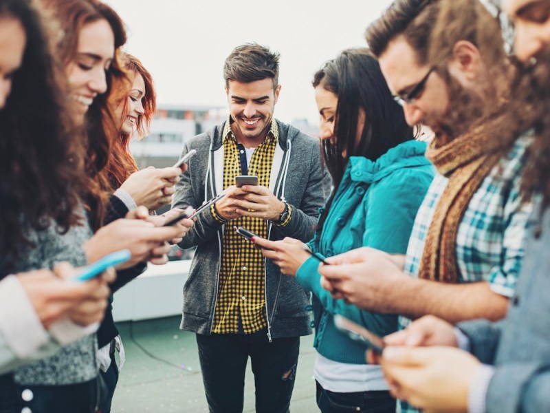 Menschen mit einem Smartphone stehen im Kreis