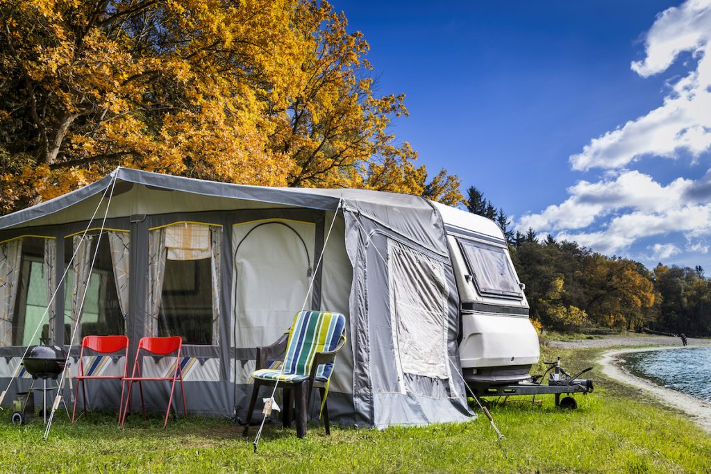 Ein Zelt neben einem Wohnwagen auf einer Wiese