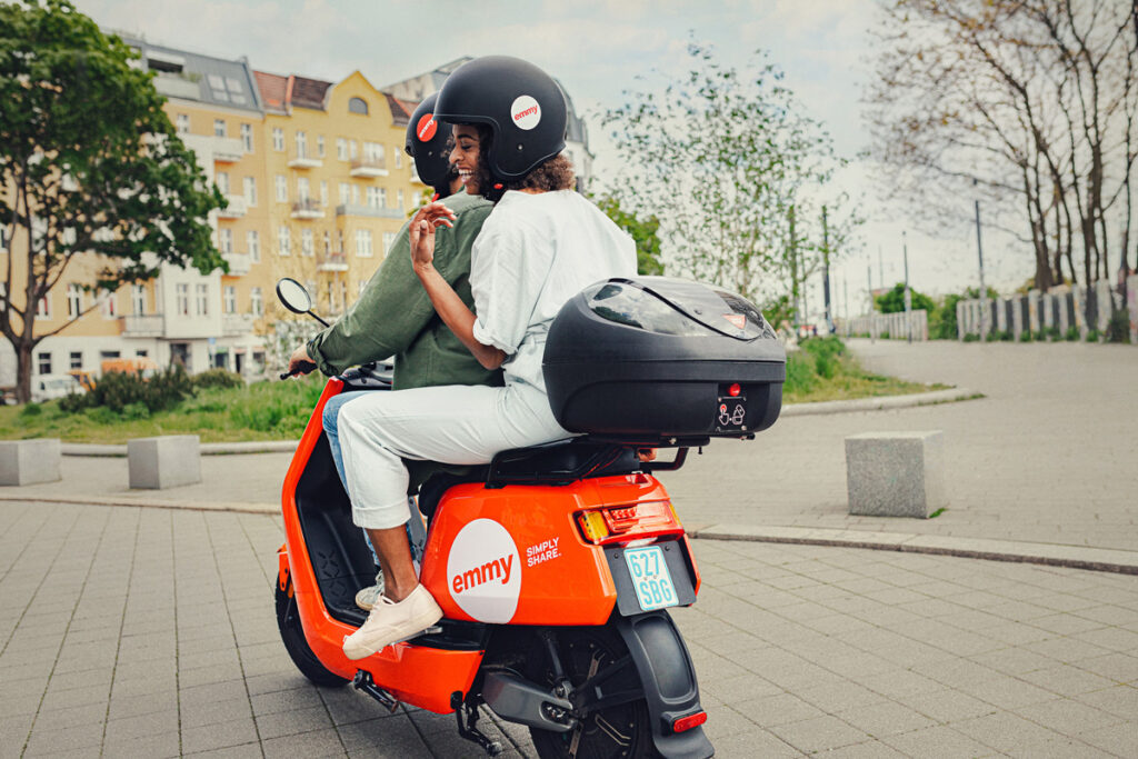 Zwei Personen fahren auf einem E-Roller.