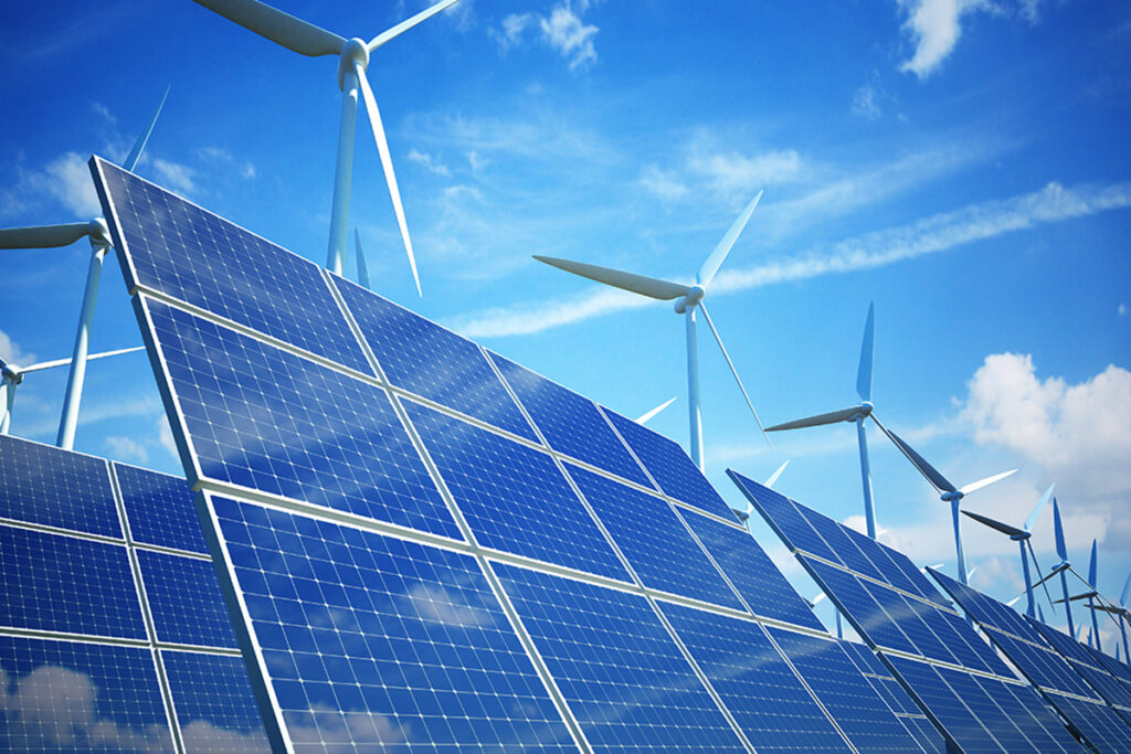 Solarzellen und Windräder dahinter vor blauem Himmel