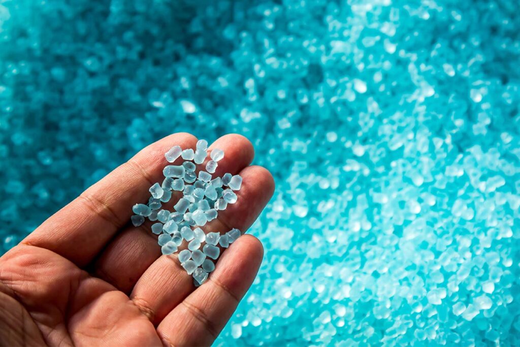 Hand mit blauen Teilchen vor Becken mit ganz vielen blauen Teilchen