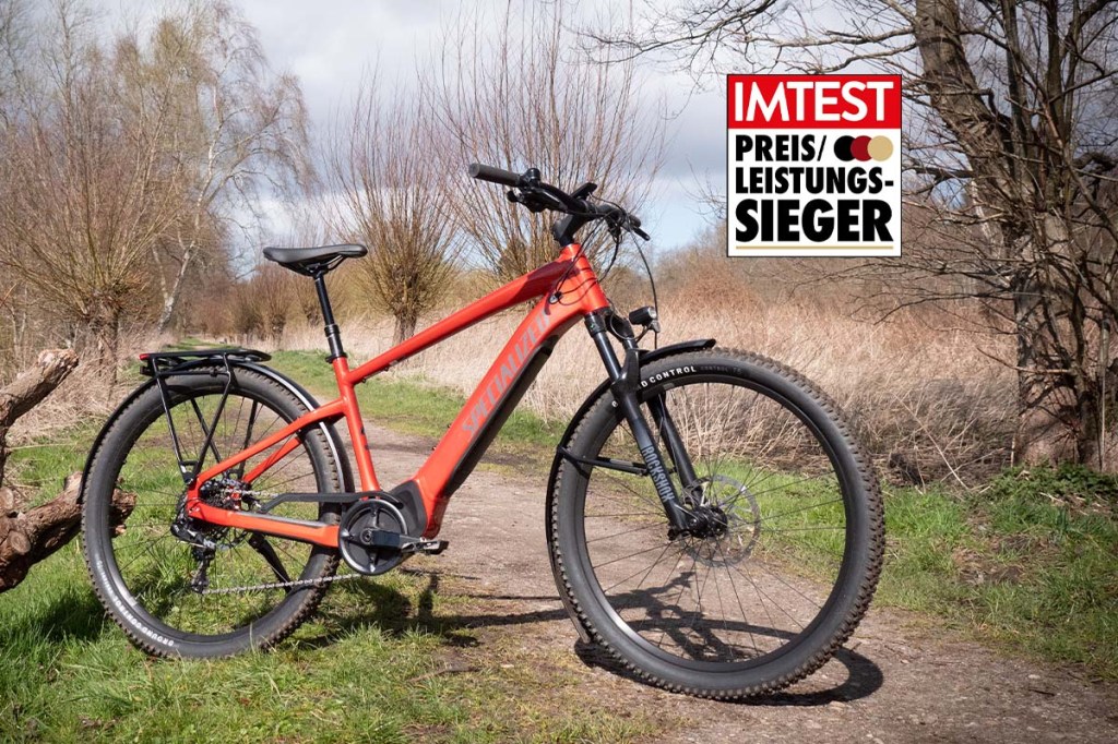 rotes E-Mountainbike an einem Feldweg stehend, mit Preis-Leistungs-Sieger-Siegel