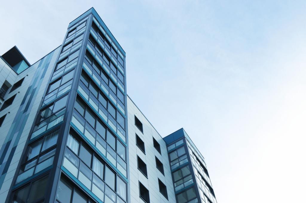 Hohes Bürogebäude mit vielen Fenstern von unten vor blauem Himmel