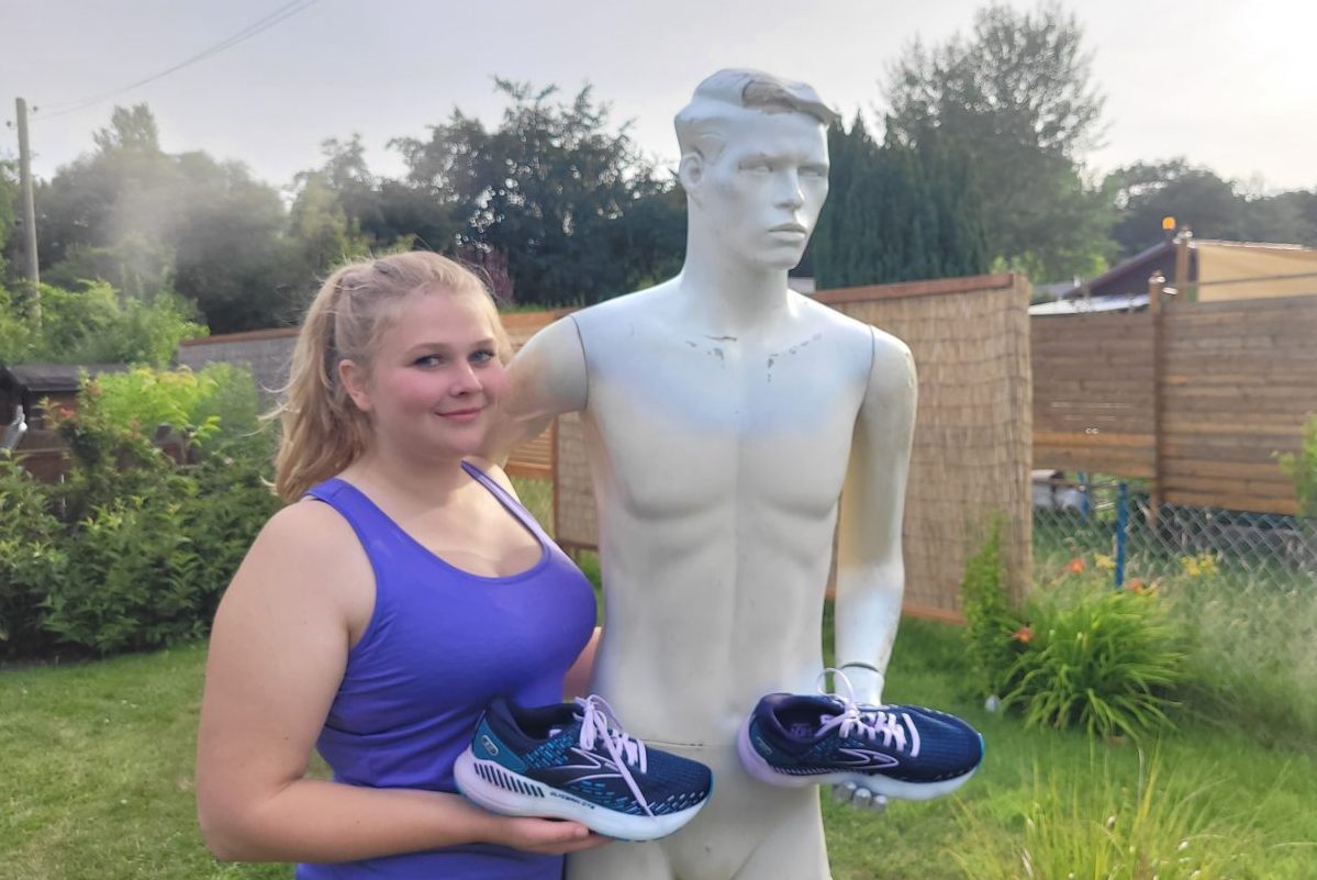 Eine Leserin mit einem lila Top neben einer Schaufensterpuppe mit dem Testschuh in der Hand.