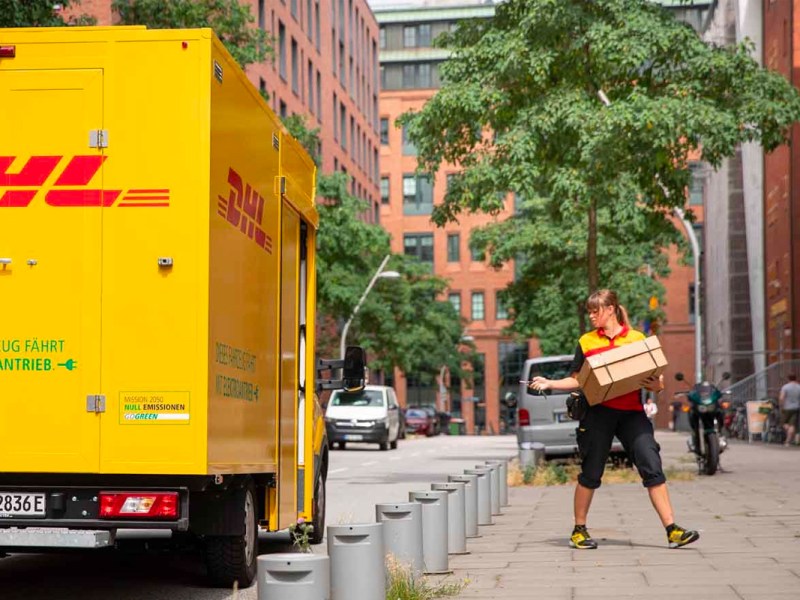 Eine Postbotin schließt ein DHL-Fahrzeug in der Hafencity ab.