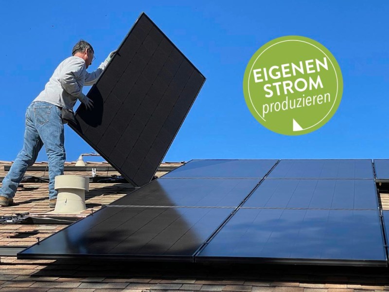 Ein Mann steht auf einem Dach und bringt ein Solarpanel an.