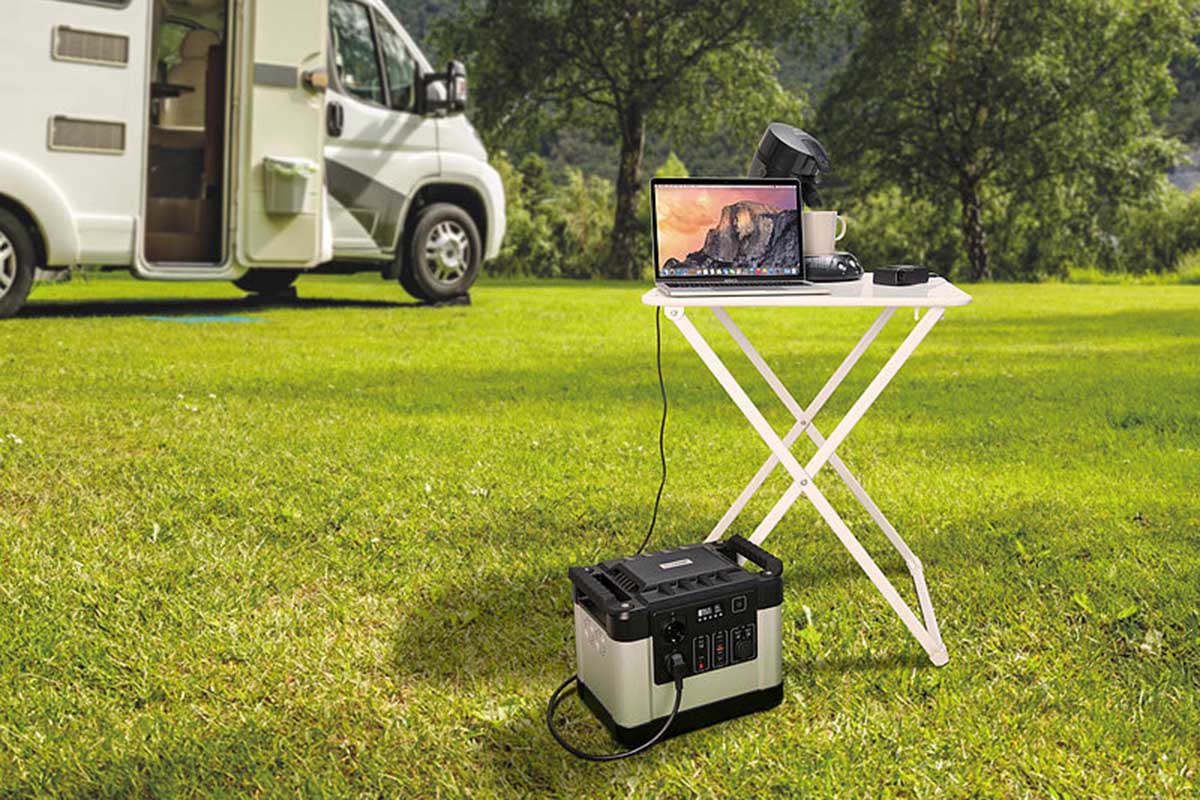 Ein Revolt Solargenerator steht vor einem Campingtisch mit Laptop.