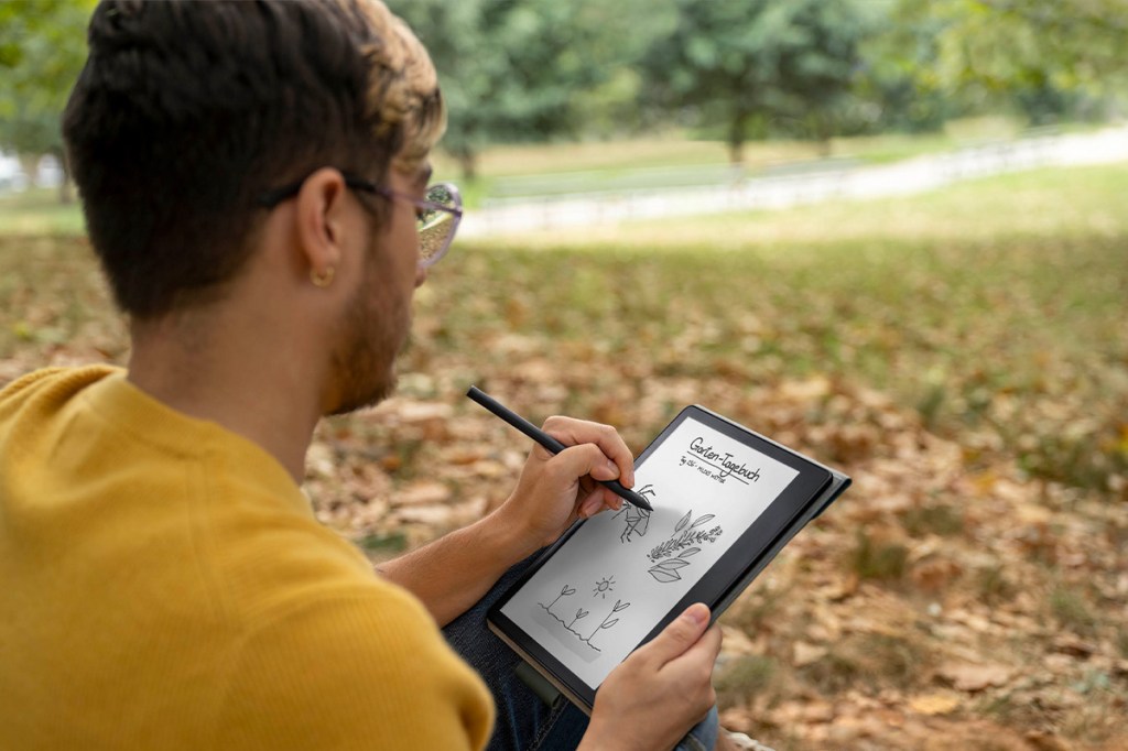 Eine Person sitzt im Park und schreibt etwas auf dem Amazon Kindle Scribe.