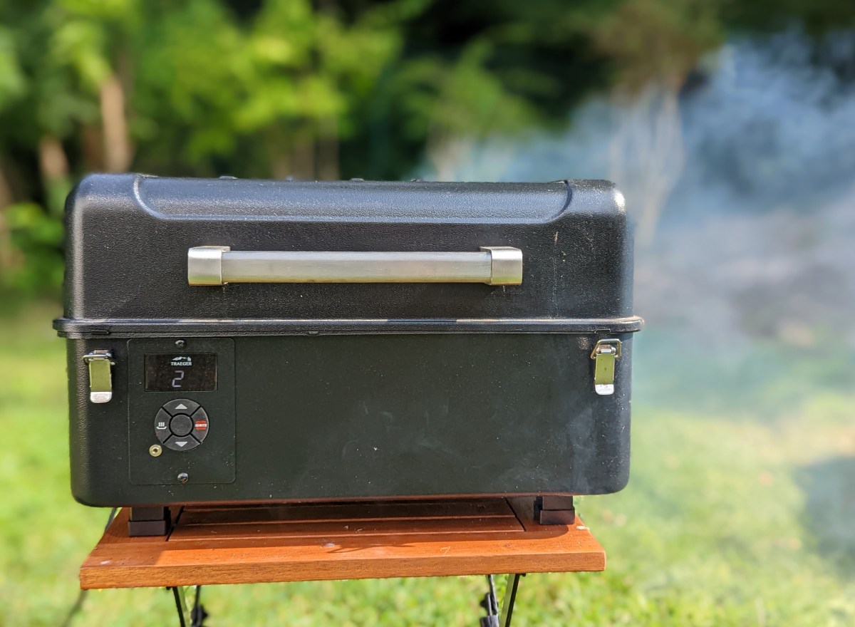 Der Pelletgrill auf einem Tisch im Betrieb. Der Deckel ist geschlossen, es ist Rauch zu sehen