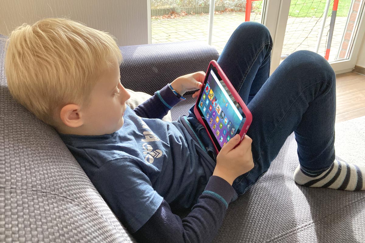 Kind sitzt auf Sofa mit Amazon Fire HD 8 Kids Pro in den Händen