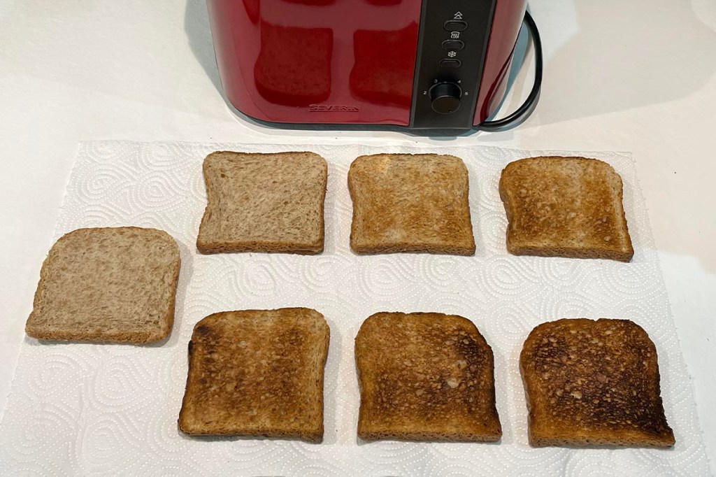 Sieben Toastscheiben unterschiedlich gebräunt, oben im Bild roter Toaster