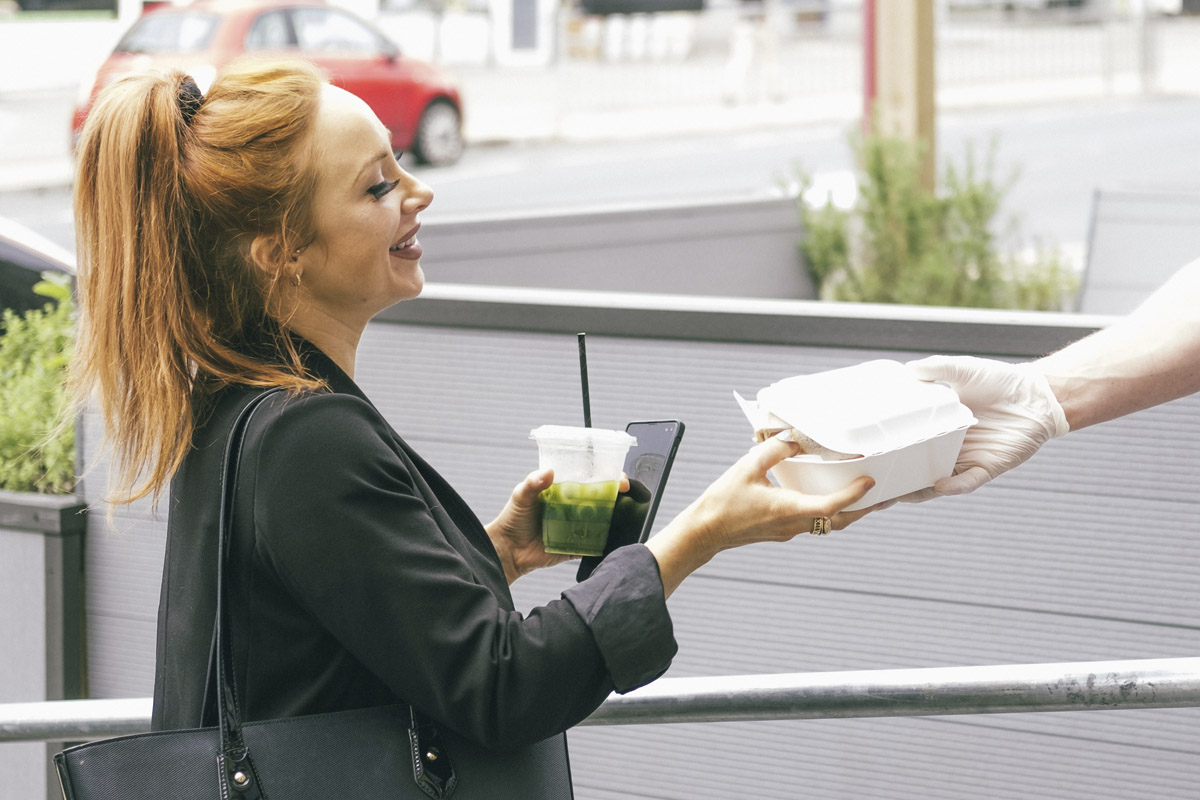 Eine Frau nimmt auf der Straße Essen entgegen.