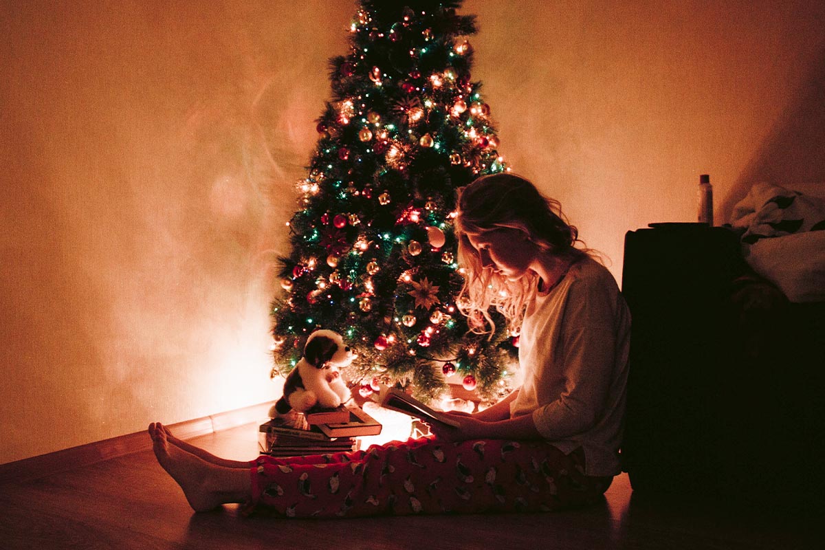 Frau sitzt neben Tannenbaum auf dem Boden