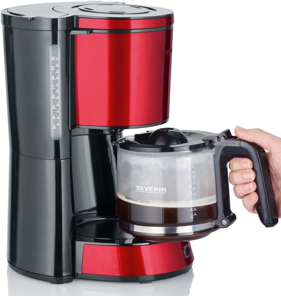 Eine Hand umgreift den Henkel der befüllten Kaffeekanne und zieht diese von der Wärmeplatte der roten FIltermaschine von Severin.
