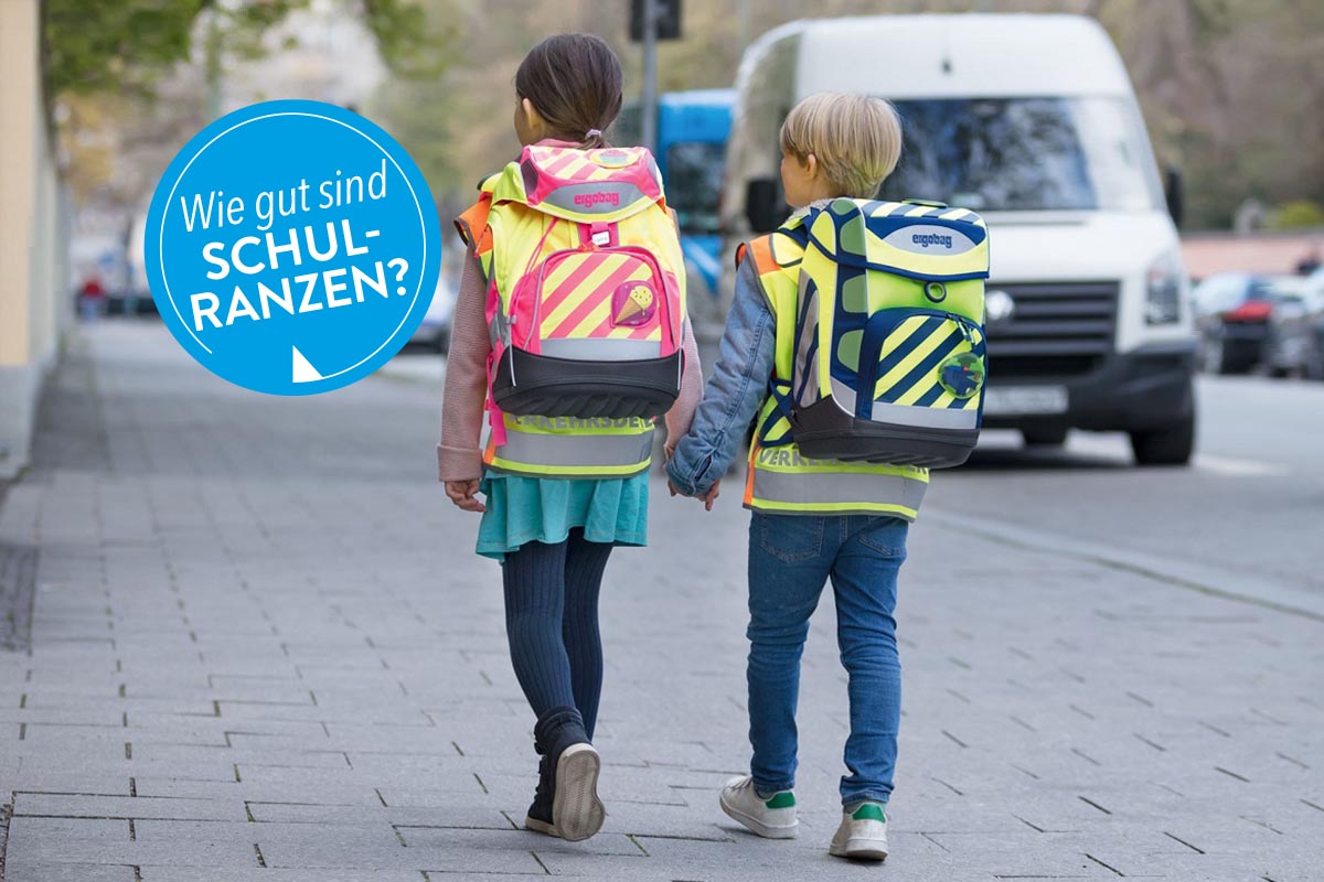 Zwei Kinder mit Schulranzen auf einem Gehweg