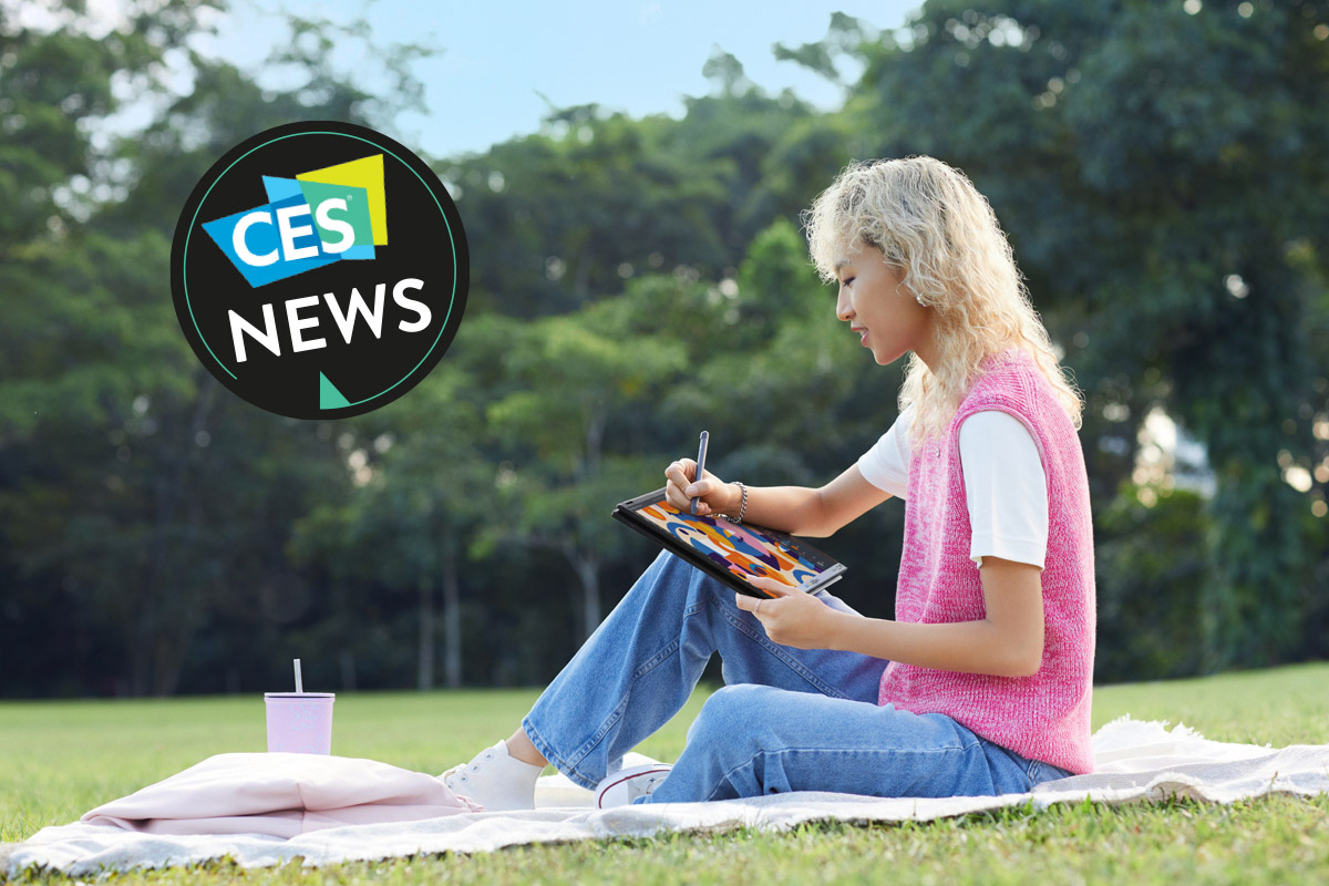 Eine Frau sitzt mit einem Notebook in einem Park.