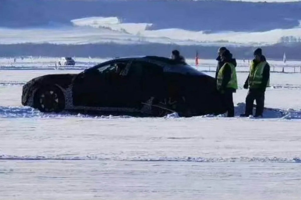 Xiaomis E-Auto im Schnee, daneben Menschen in Sicherheitsvesten