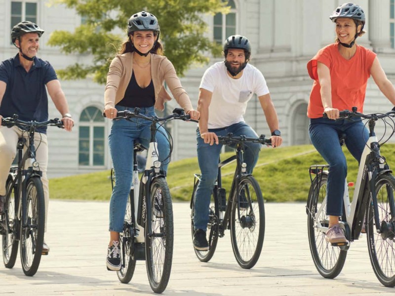 vier Fahrradfahrer fahren nebeneinander in einer städtischen Umgebung