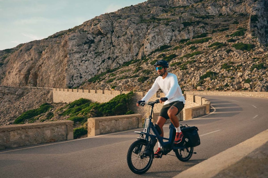 Mann fährt auf einem Kompakt-E-bike von Kalkhoff auf einer Berg-Panoramastraße im Sonnenschein