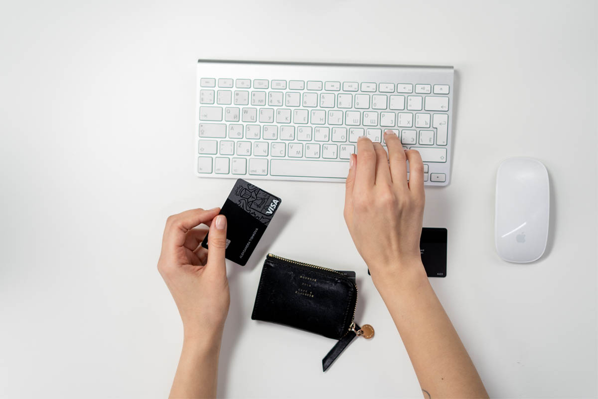 Ein Mensch mit einer Kreditkarte tippt auf einer Tastatur.