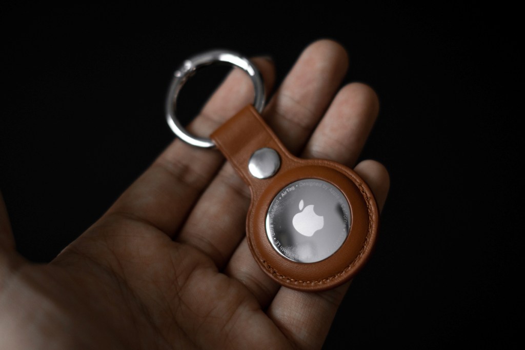 Eine Hand hält einen AirTag von Apple.