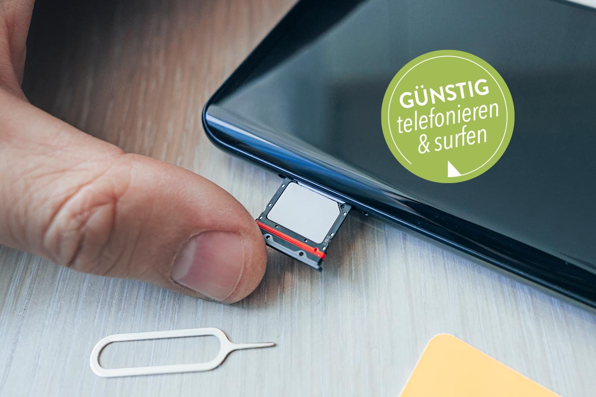 Ein Smartphone, das auf einem Tisch liegt und in das eine Sim-karte eingesteckt wird.