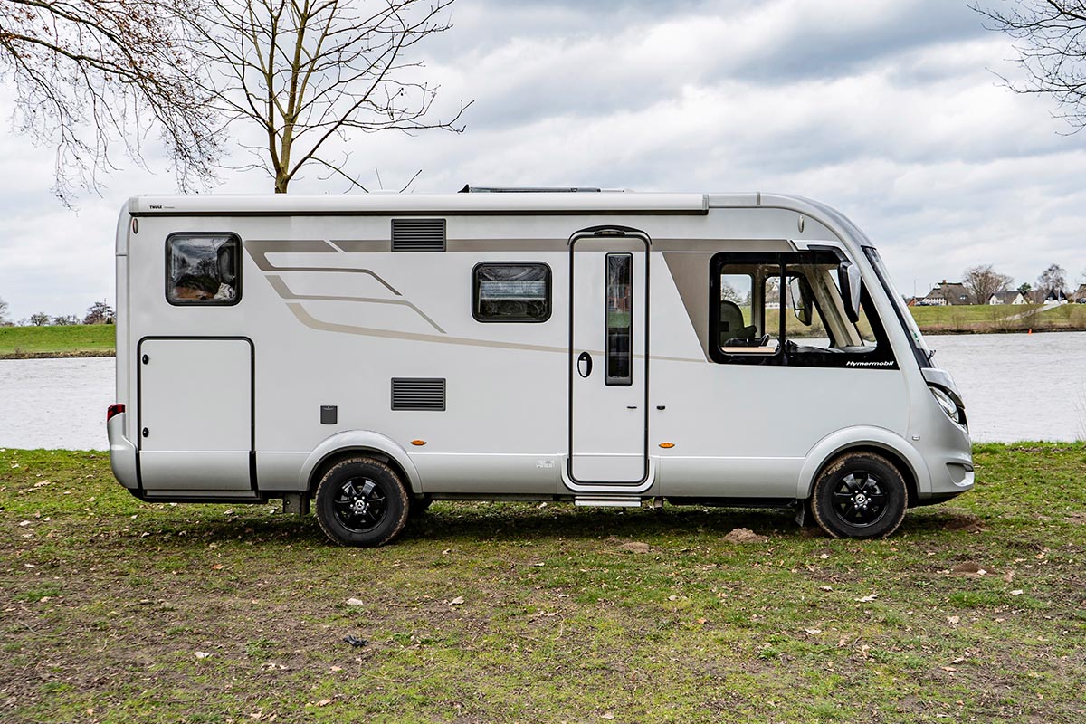 Wohnmobil im Profil vor Flusslandschaft.