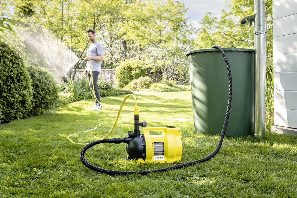 Ein Mann bewässert seinen Garten, daneben eine Wasserpumpe.