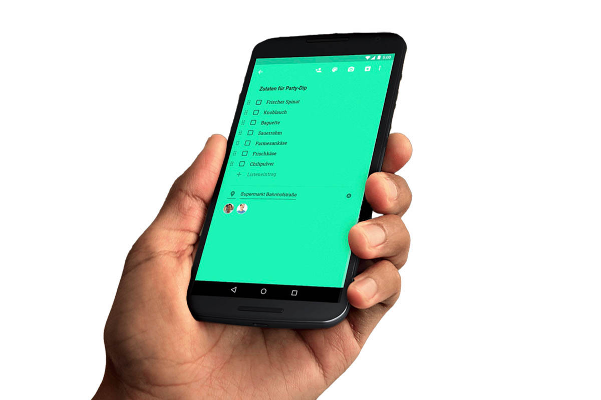 Hand hält ein Handy, auf dem eine Liste in Google Notizen mit grünem Hintergrund zu sehen ist