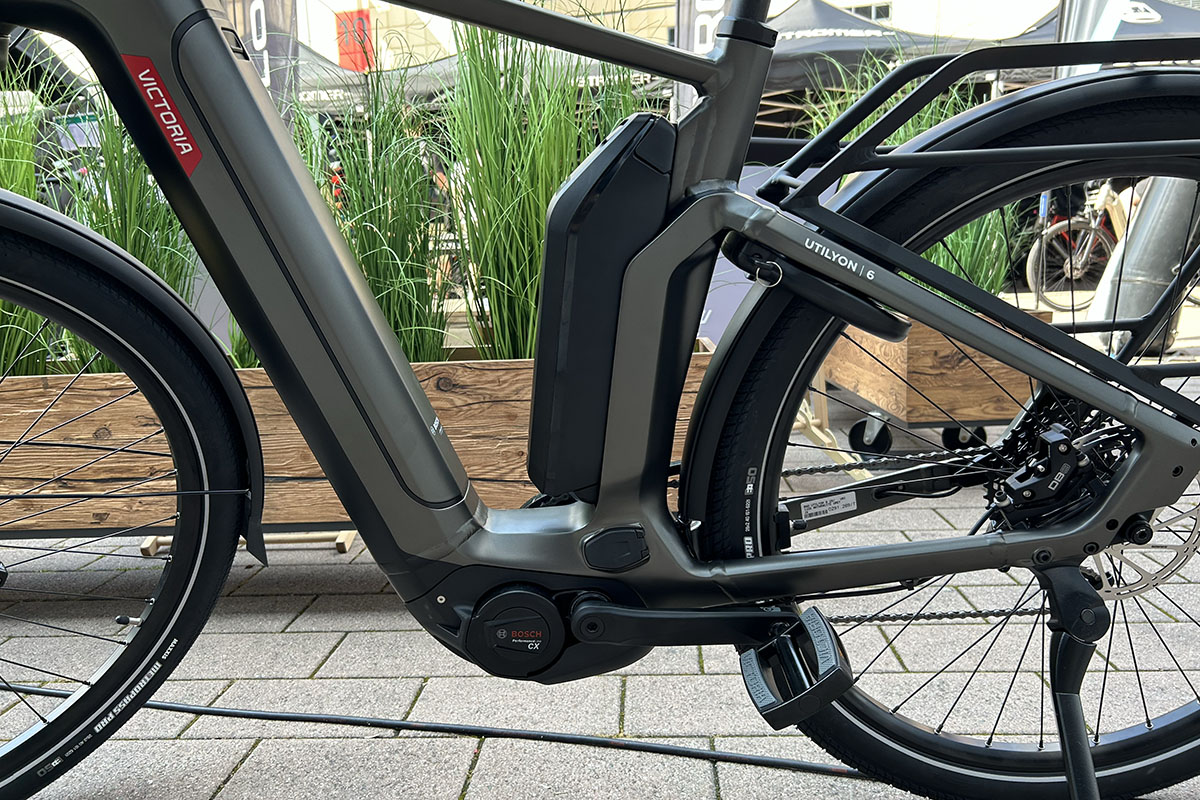 E-Bike Victoria Utilyon mit Detailansicht des zweiten Akkus, der am Sattelrohr befestigt ist  vor Messestand auf der Eurobike 2023.