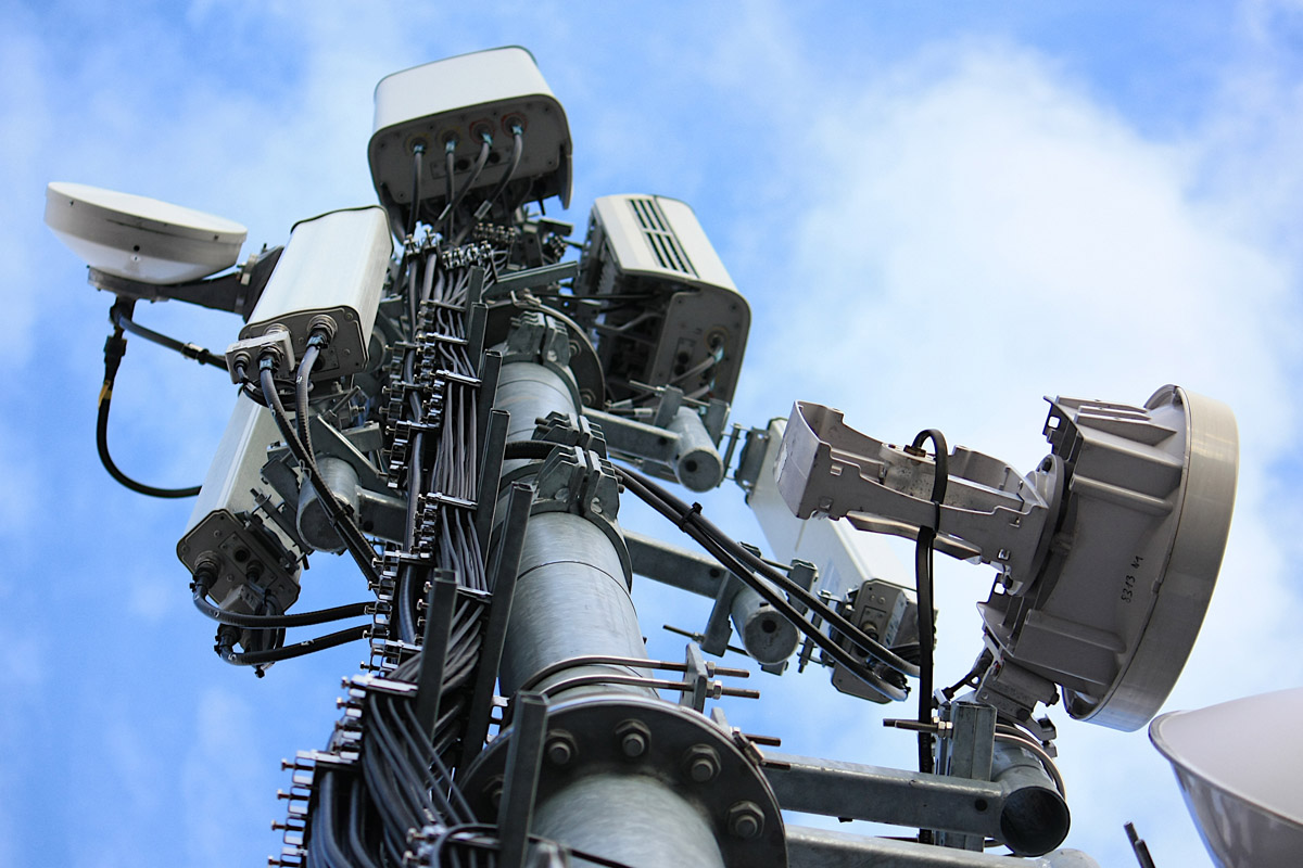 Ein Mobilfunkmast aus der Wurmperspektive, im Hintergrund blauer Himmel.