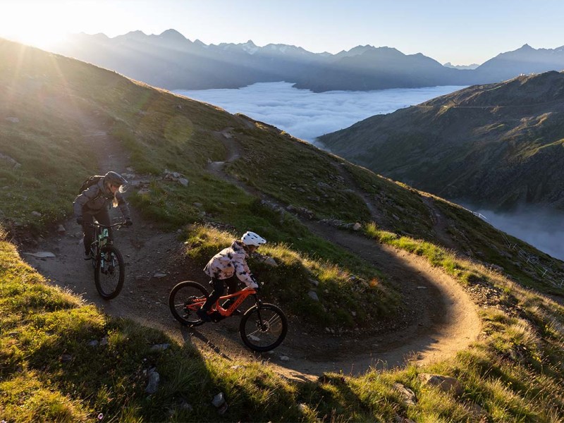 Kind fährt mit E-bike von Specialized einen Trail in einer Bergkulisse