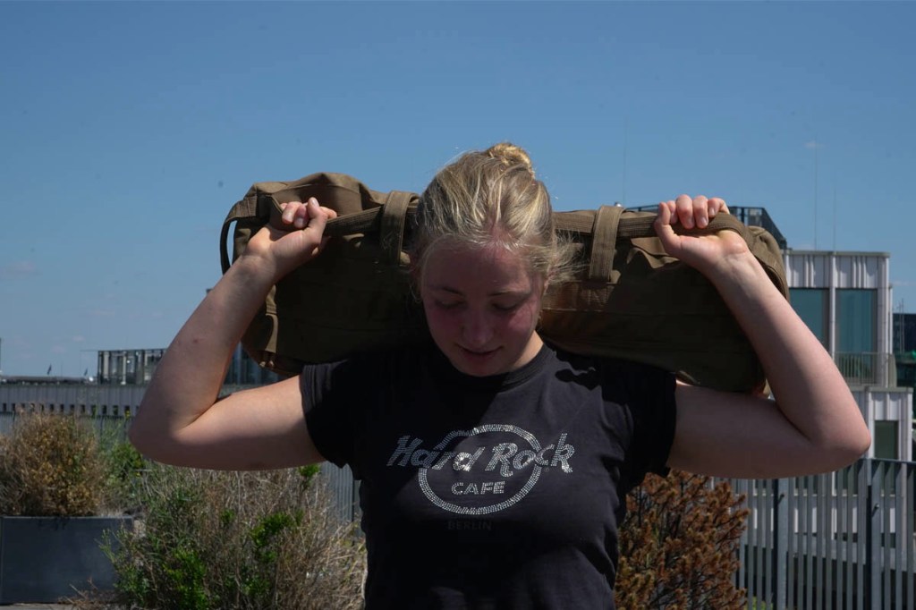 Eine blonde Frau trägt einen Go Ruck Sandsack auf den Schultern.