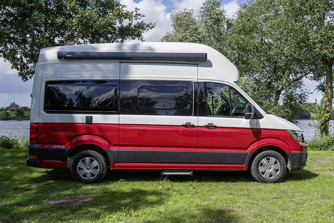 Volkswagen Grand California 600 in seitlicher Ansicht auf einem Campingplatz.