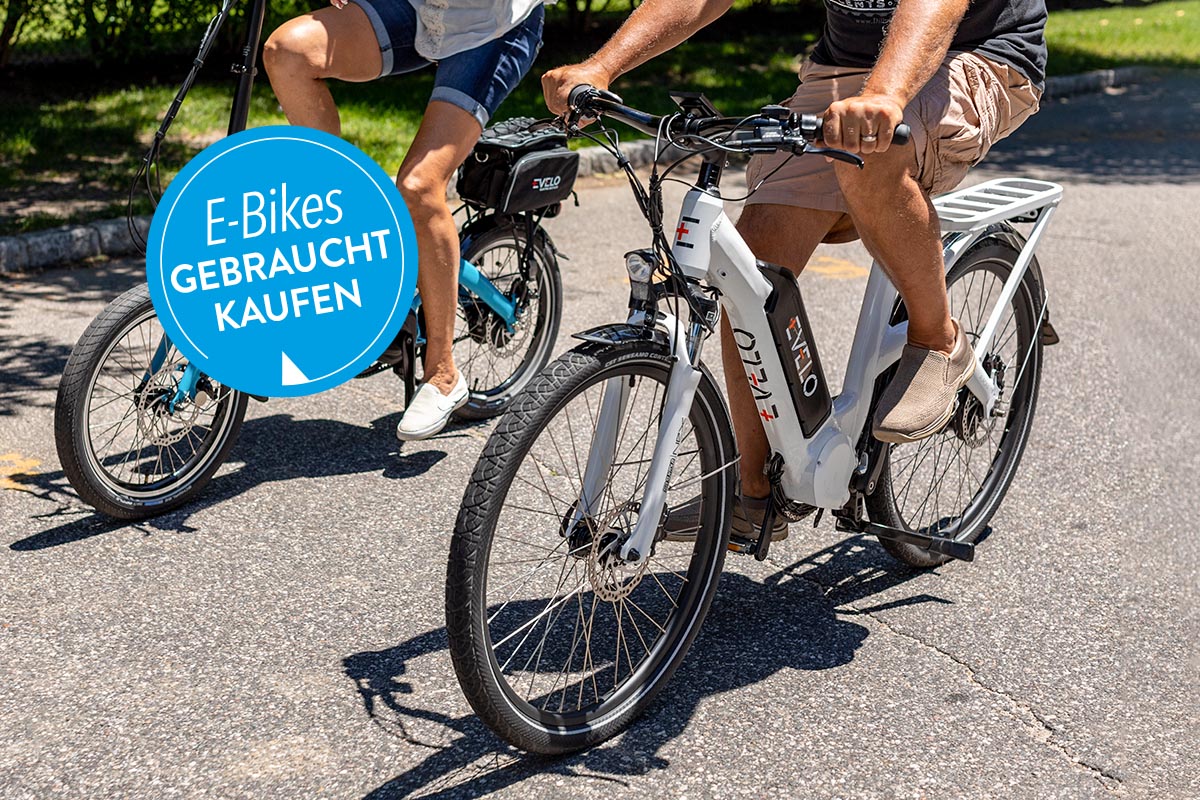 Zwei Menschen auf E-Bikes auf der Straße fahrend.