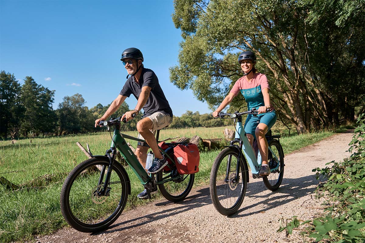 Zwei Menschen fahren mit einem E-Bike durch die Natur