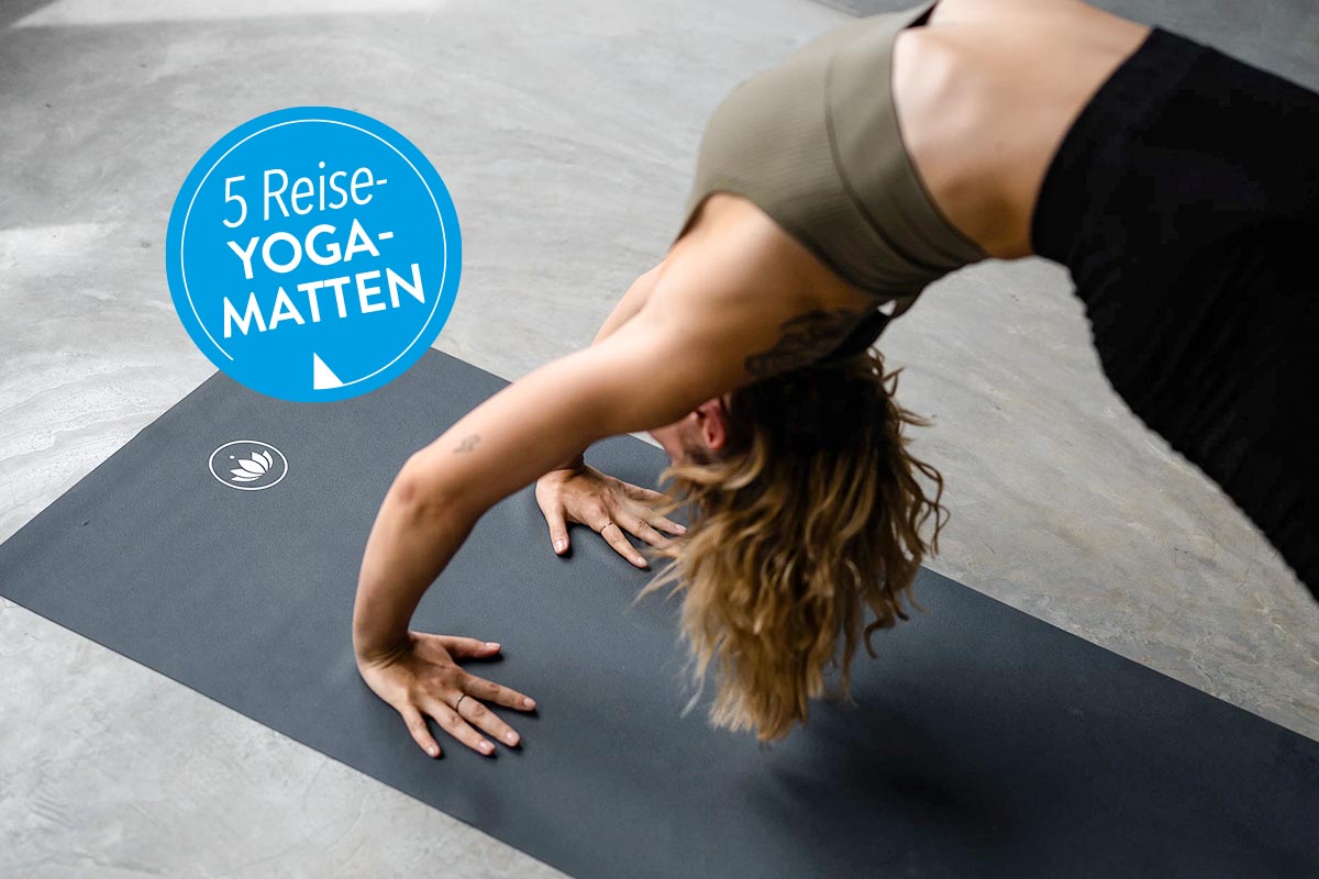 Person auf einer schwarzen Yogamatte auf dem Boden.