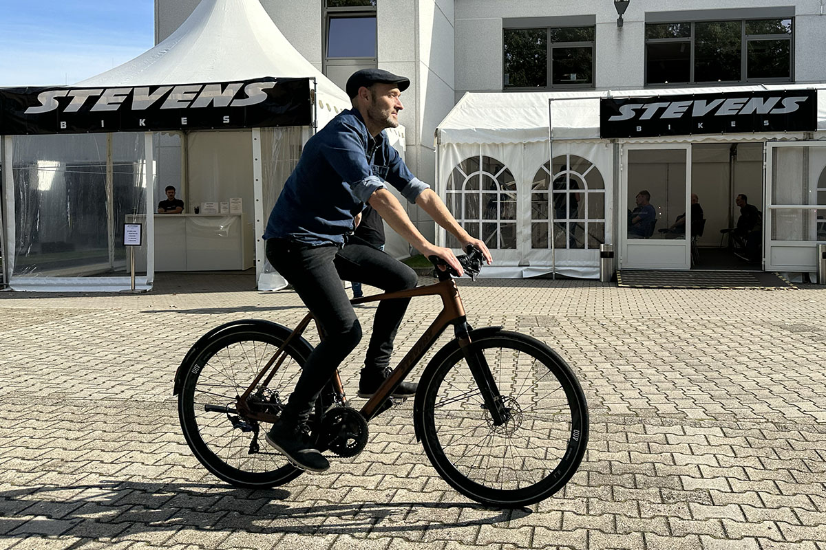 Mann fährt auf einem City-E-Bike über eine Strecke vor einem Veranstaltungszelt.