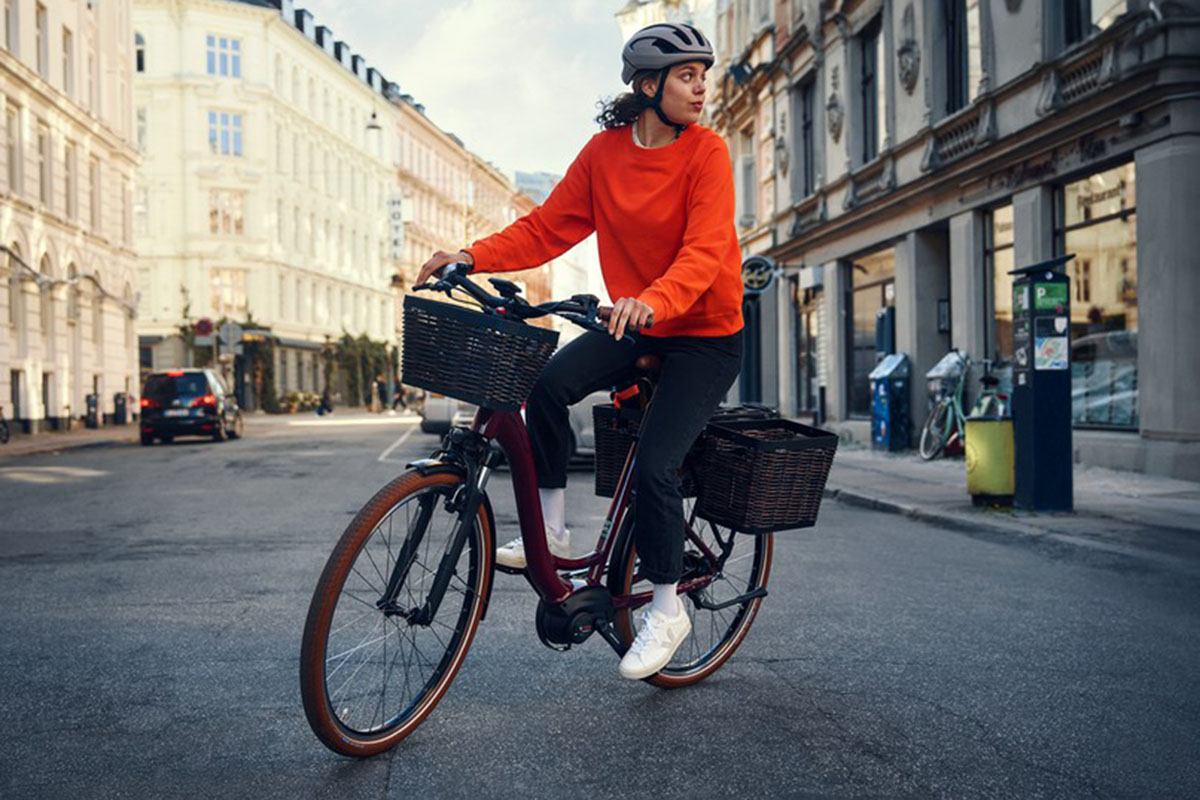 Frau fährt mit E-Bike Riese & Müller Swing4 über eine Straße in der Stadt.