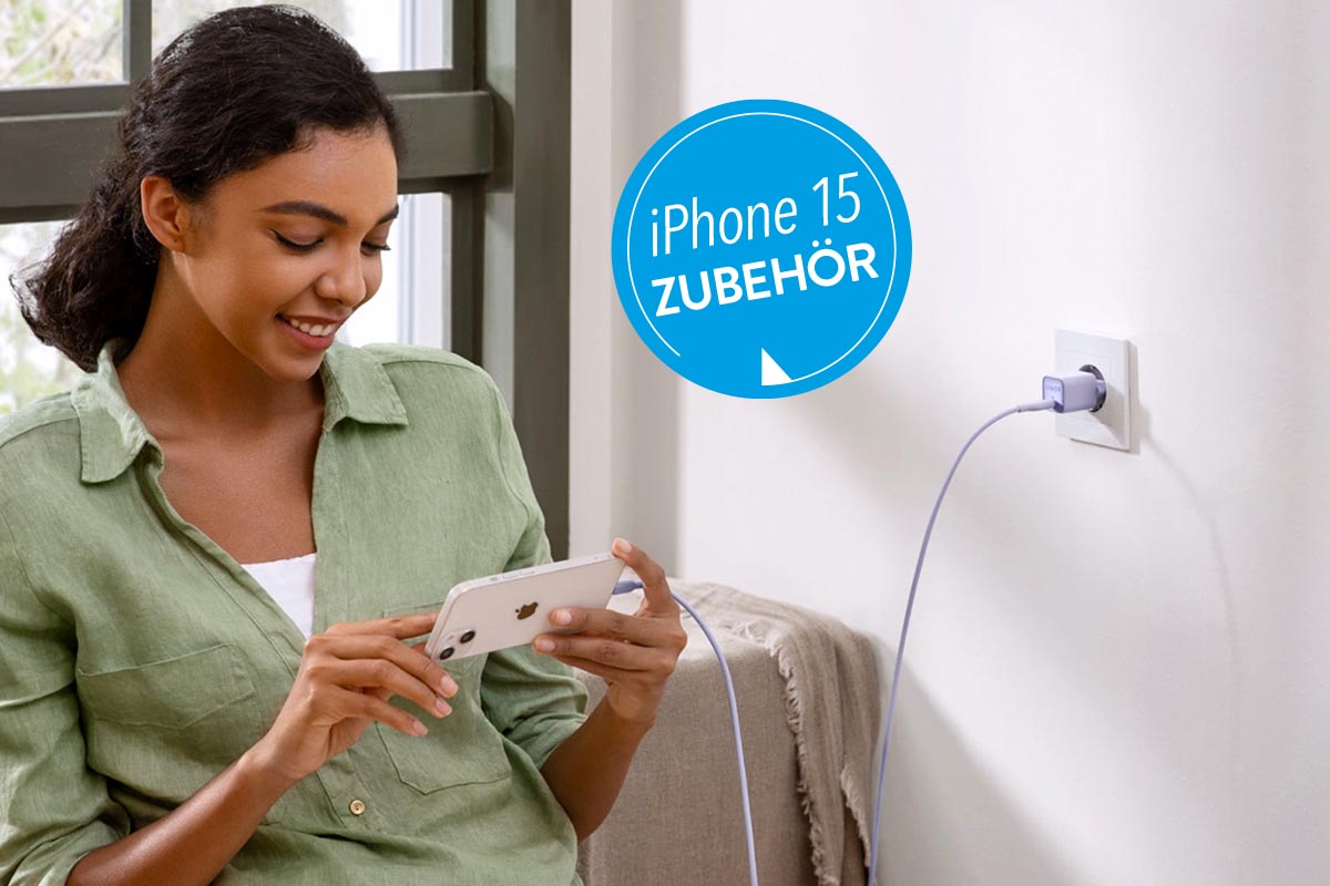 Person mit iPhone in der Hand, das an einem Kabel angeschlossen ist.