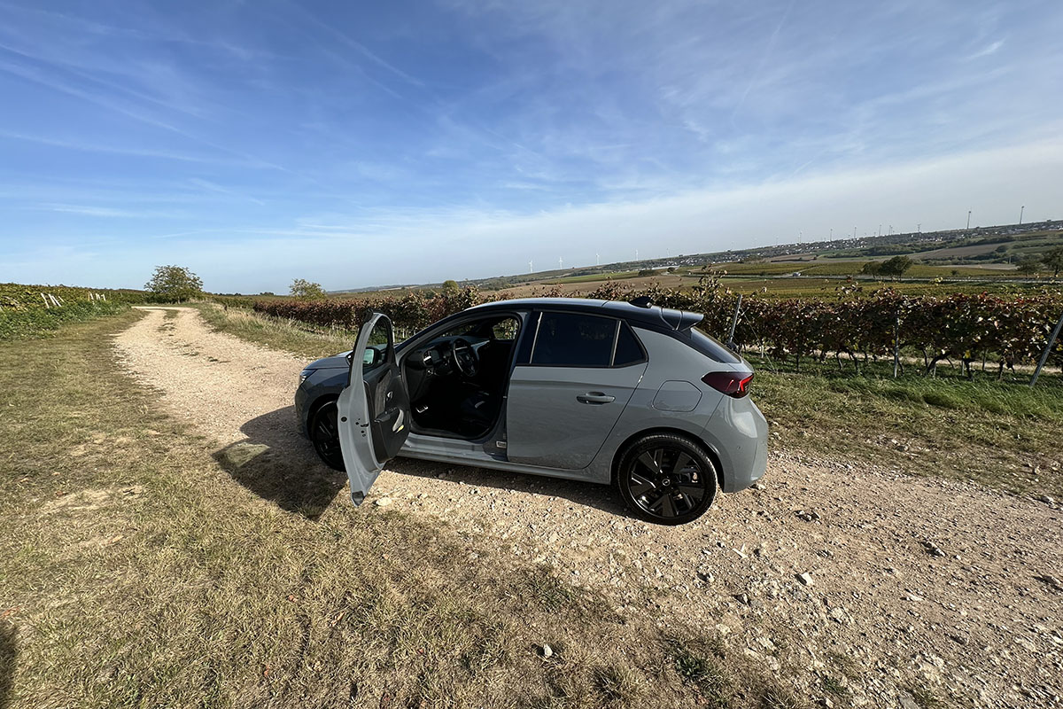 Opel E-Corsa mit geöffneter Fahrertür im Weinberg.